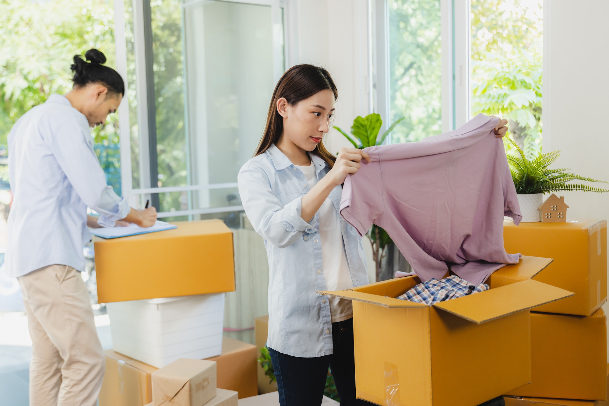 love Asian couple fold cloths into box or take it out to prepare moving new house